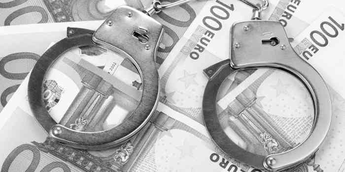 Handschellen auf Geldscheinen - bildlich für Verhaftung im Strafrecht